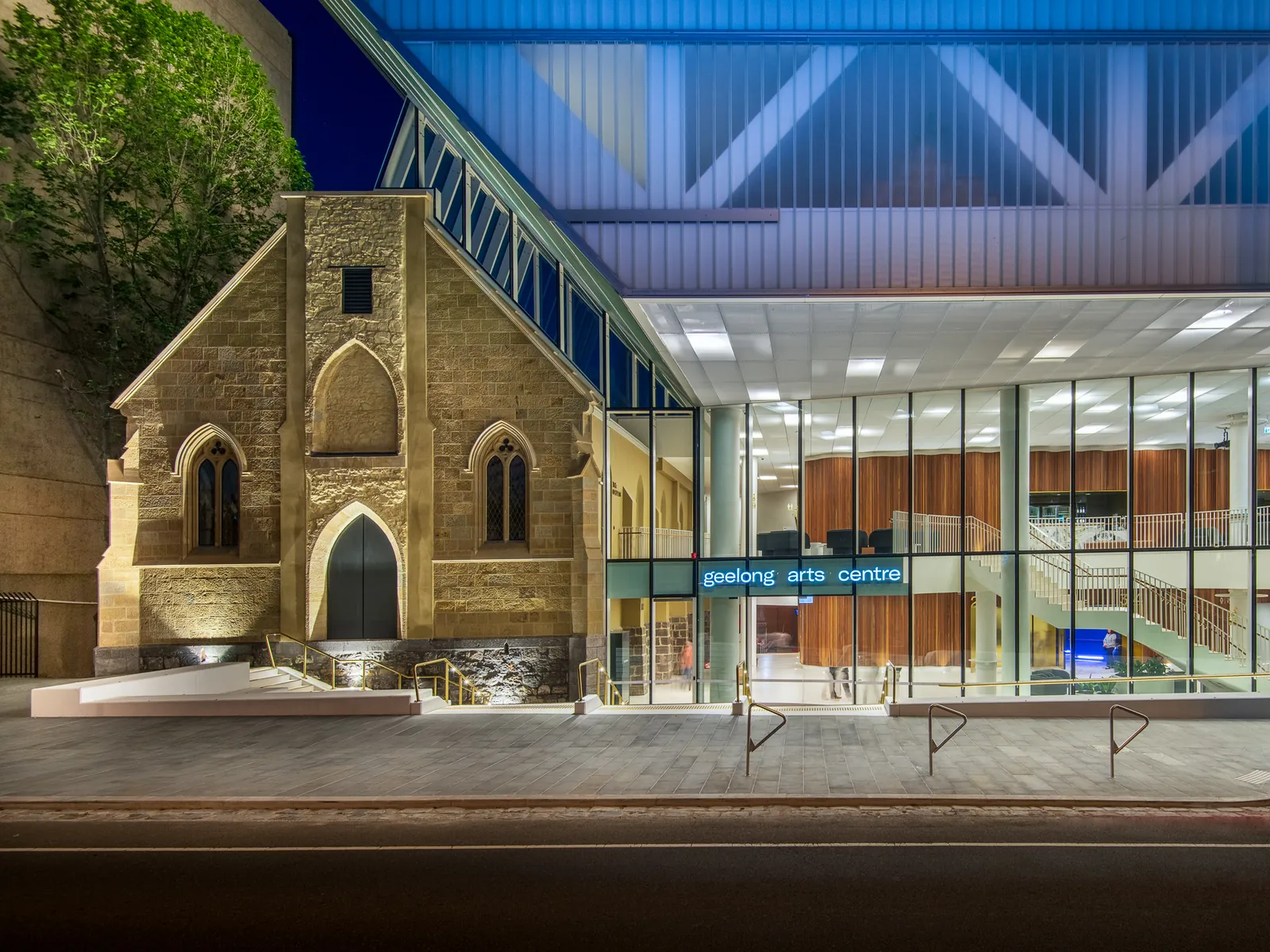Twilight photo of the Geelong Arts Centre, heritage church facade beside the new glass atrium